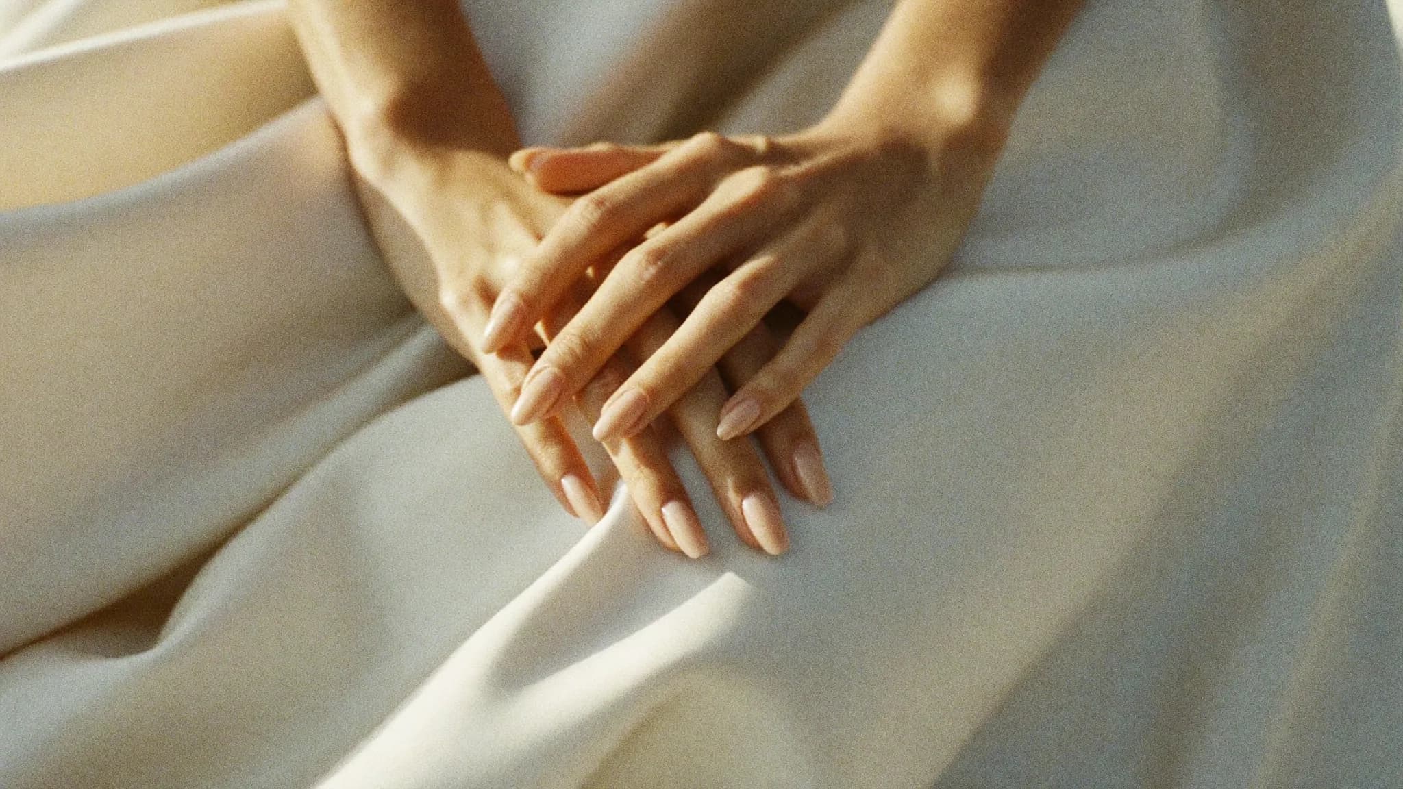 Manos con manicure nude sobre seda, fotografía editorial de Cala